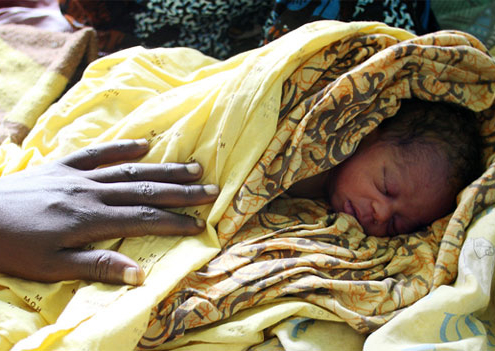 Das wenige Stunden alte Baby von Margret Khomera wird in Tücher gehüllt im Bett der Mutter untergebracht.